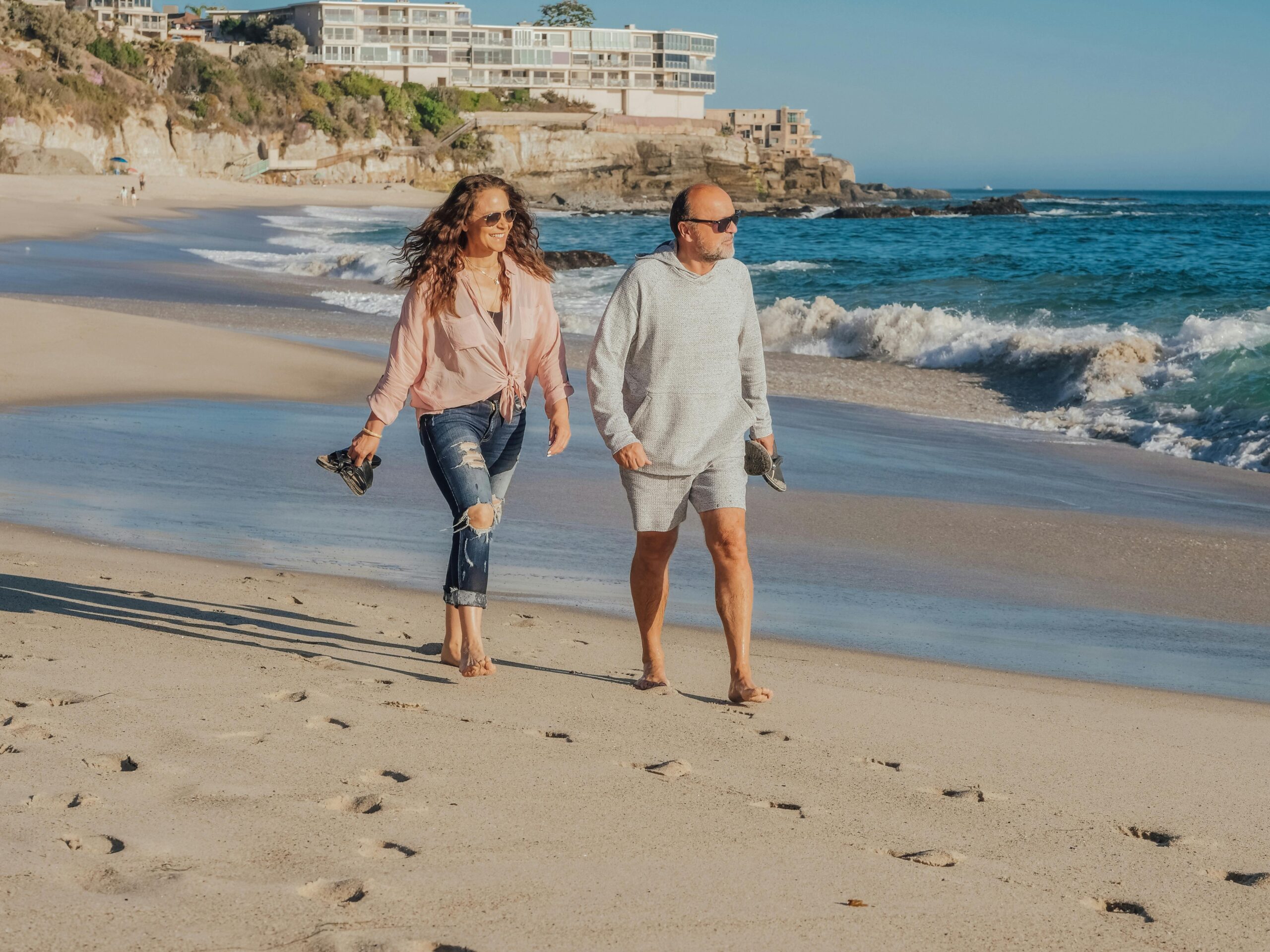 A retired couple happily walks along the Santa Cruz beach enjoying the fruits of retirement planning.